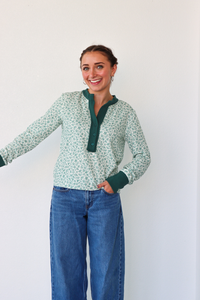 Woman wearing a green and white patterned shirt with a green collar against a white background