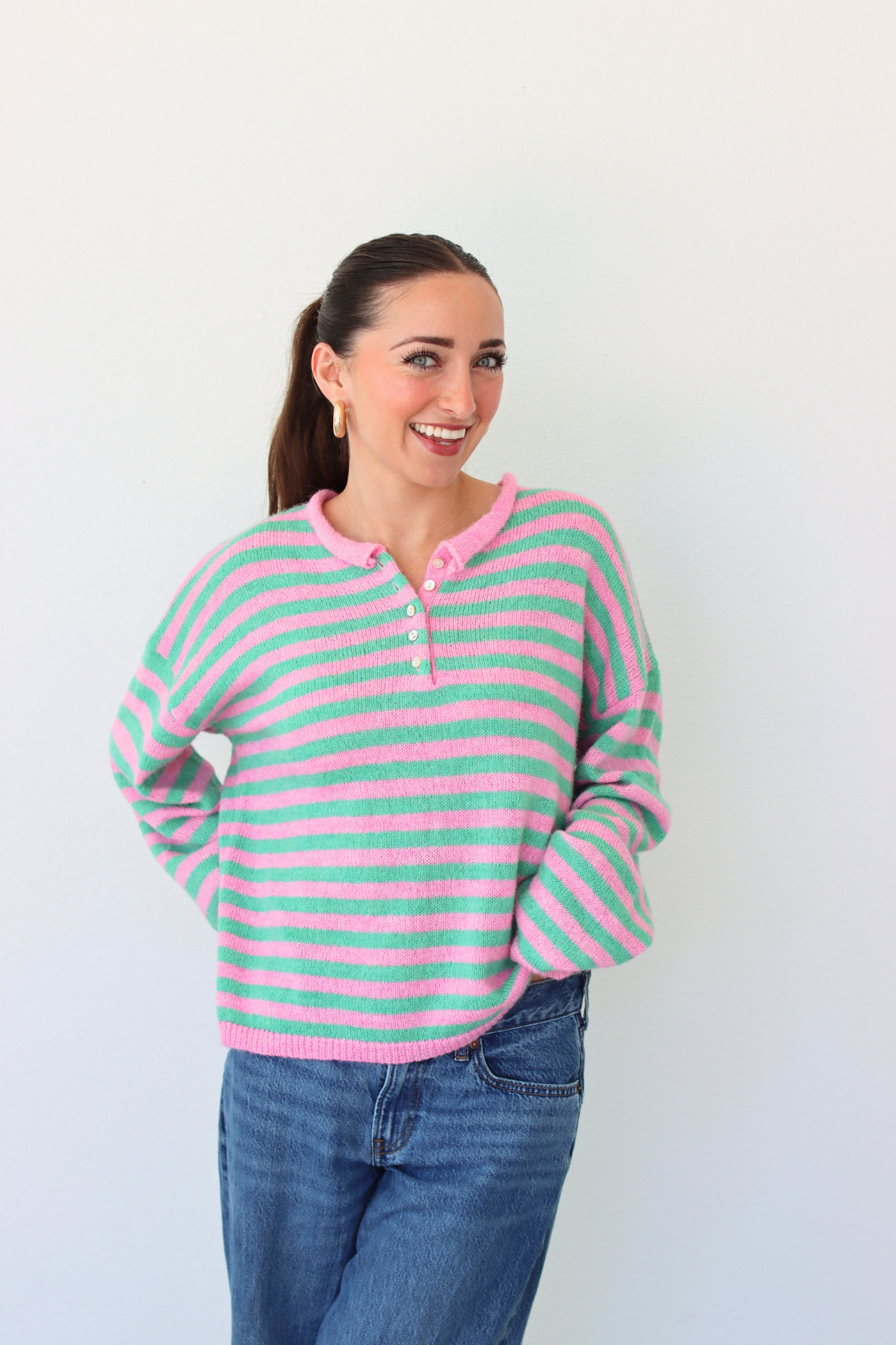woman wearing a green and pink stripe sweater against a white background