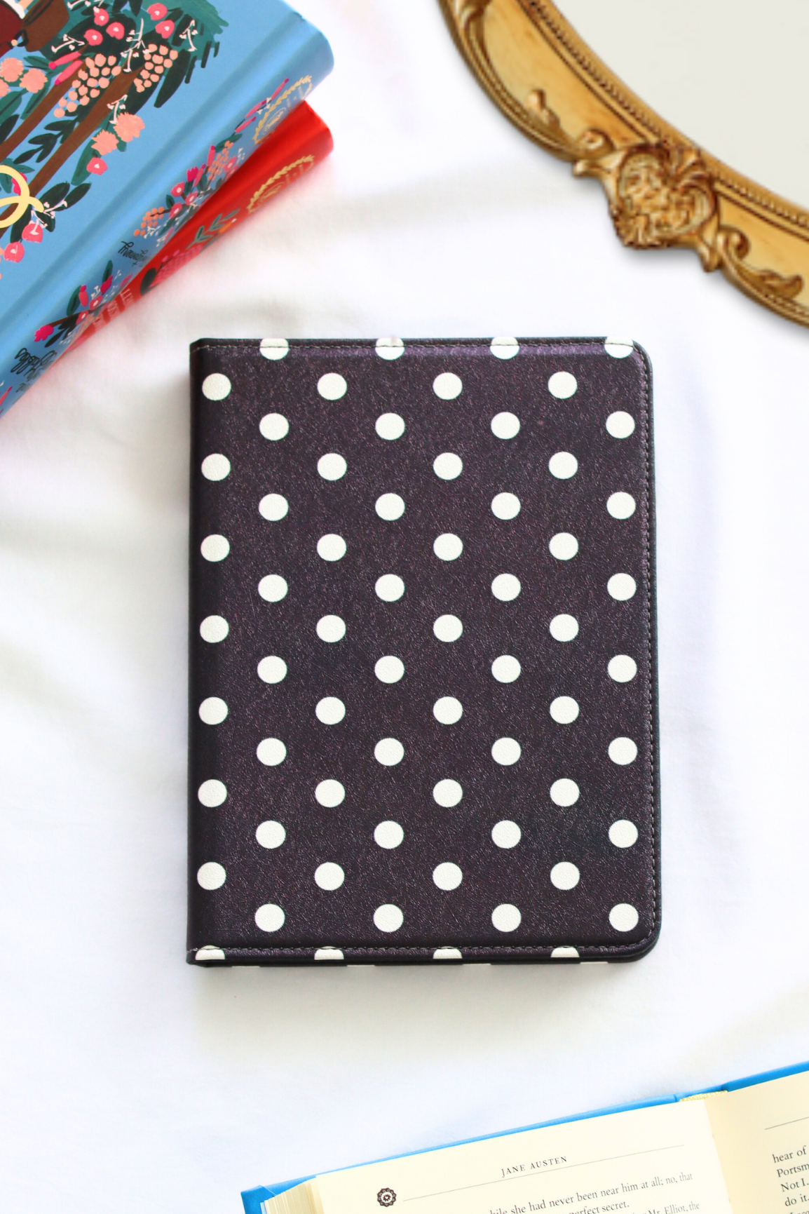 Polka dot kindle on a white surface with books and a decorative object in the background