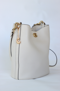 White handbag with gold accents on a light gray background