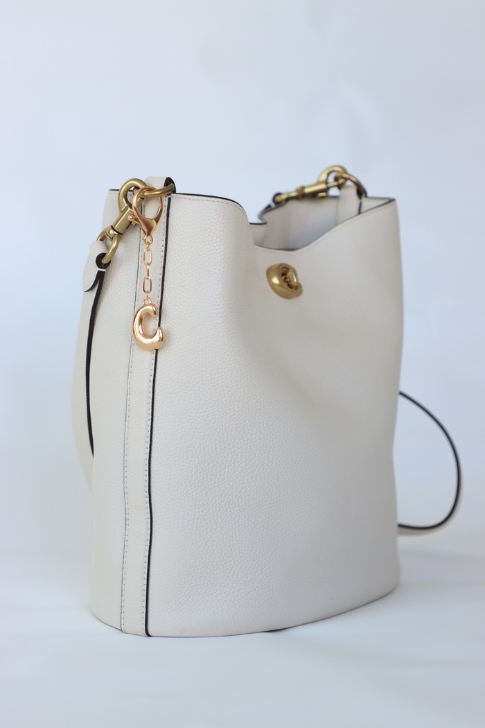 White handbag with gold accents on a light gray background