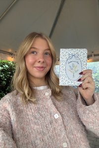 Person holding a card with a floral design outdoors