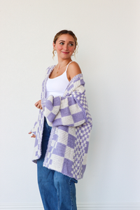 Woman wearing a purple and white checkered cardigan against a white background