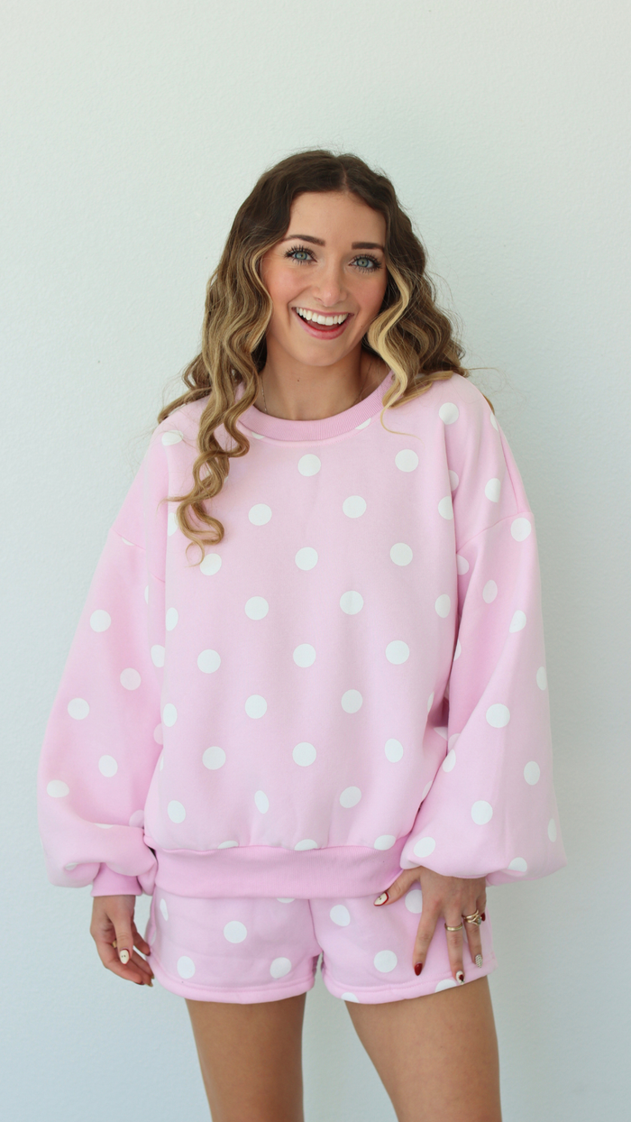 Woman wearing a pink polka dot outfit against a white background