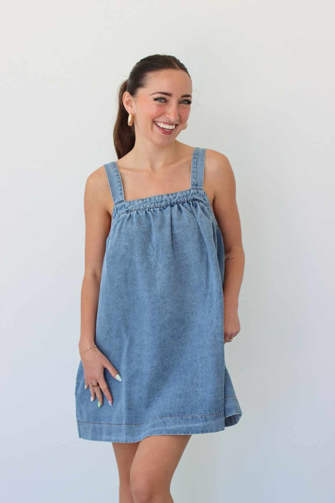 Woman wearing a denim blue mini dress against a white background