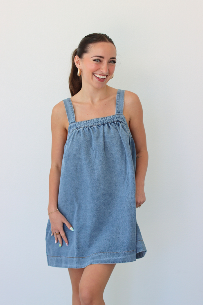 Woman wearing a denim blue mini dress against a white background