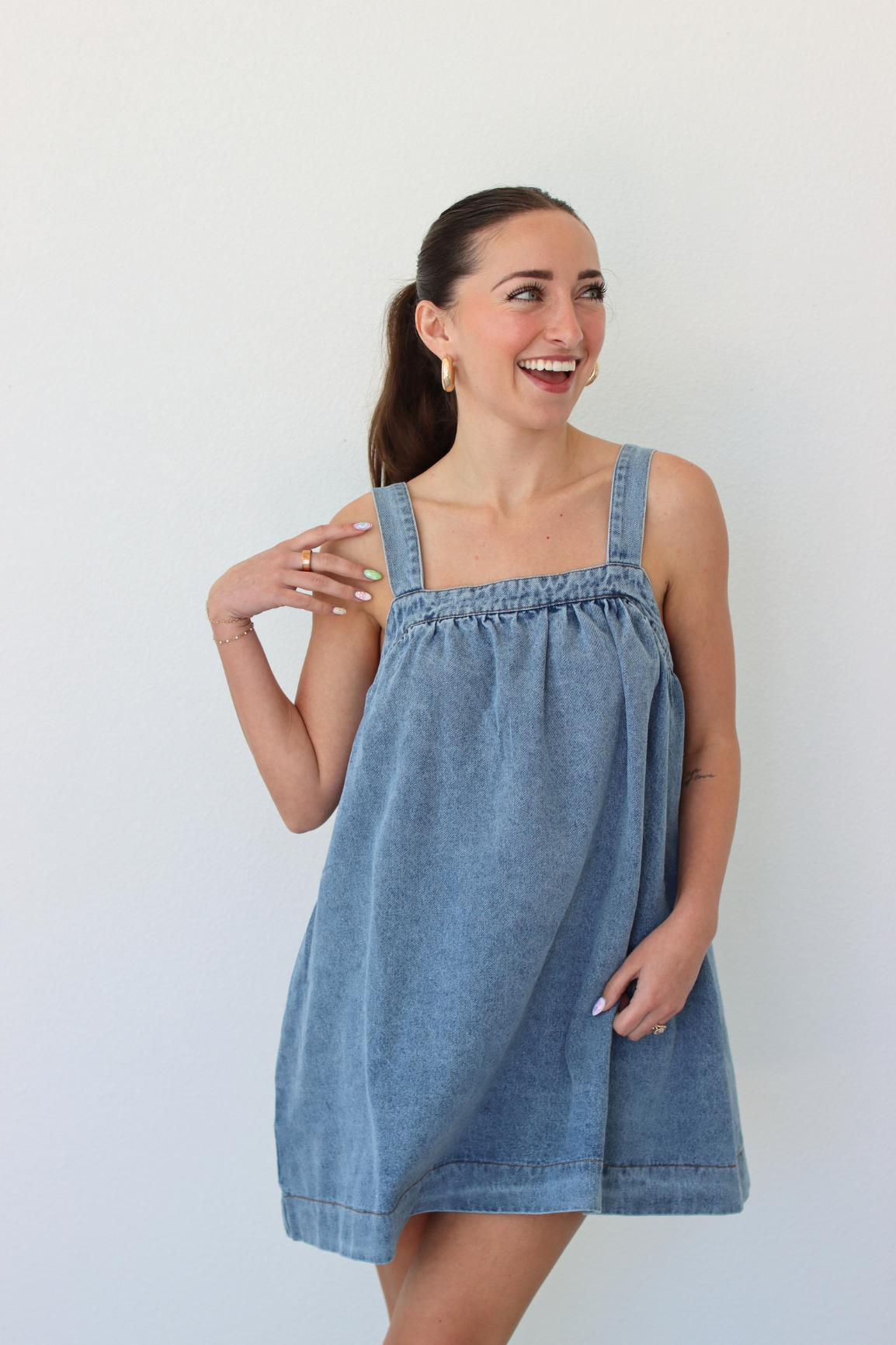 Woman wearing a denim blue mini dress against a white background