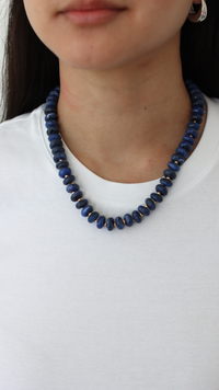 blue necklace on a woman wearing white shirt 