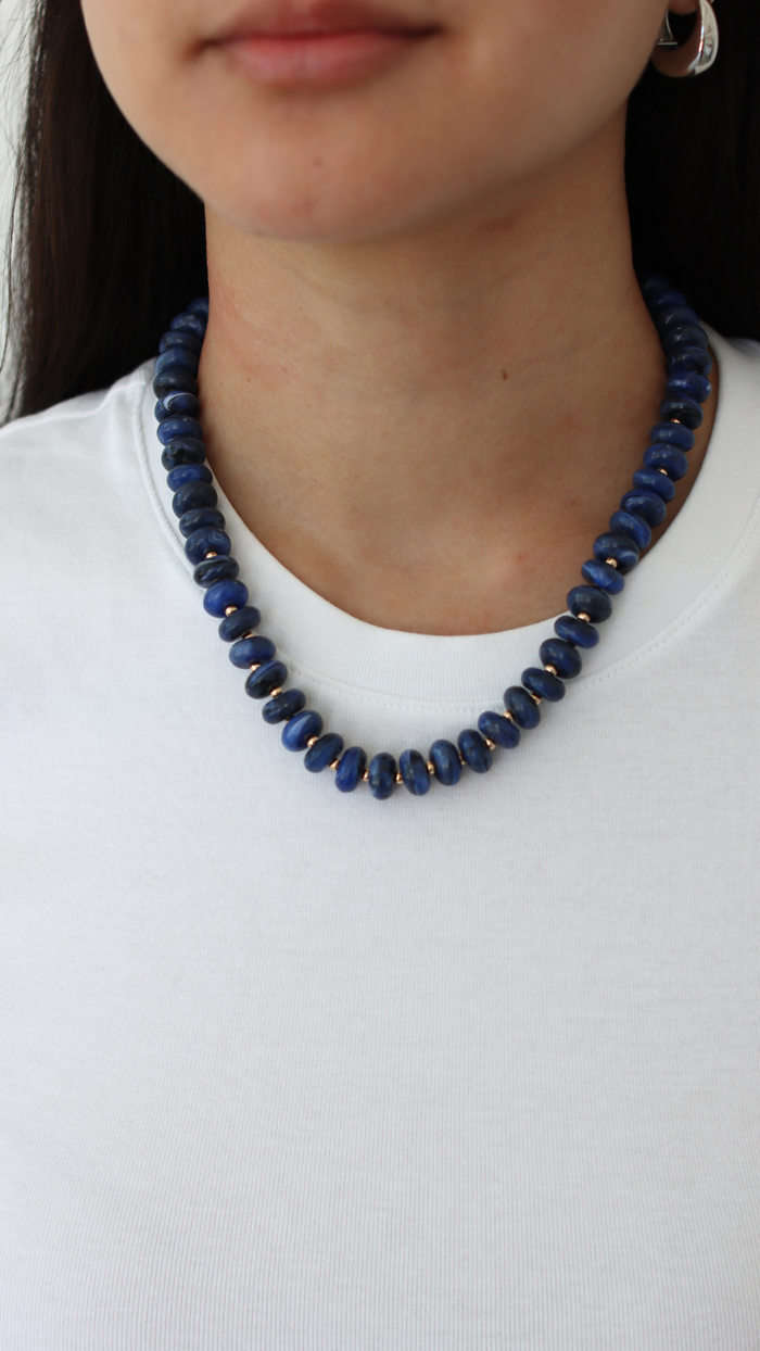 blue necklace on a woman wearing white shirt 