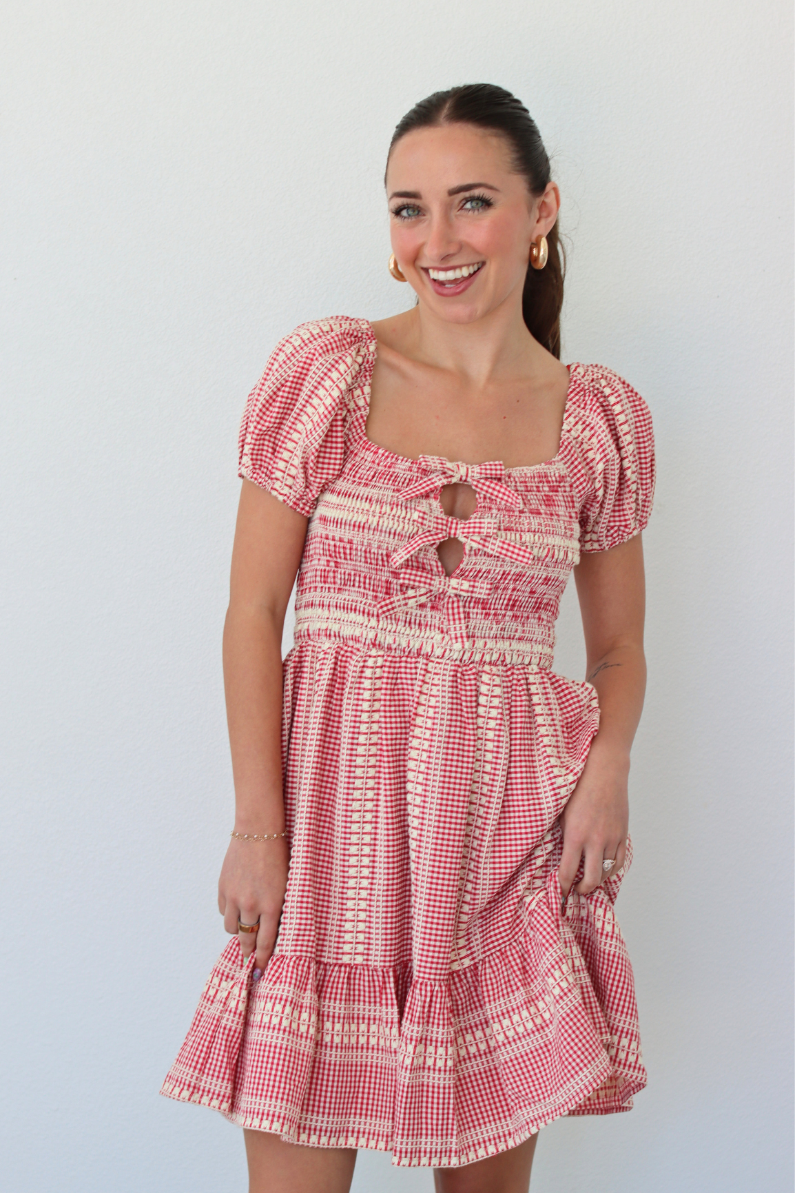 Woman wearing a red gingham mini dress with puff sleeves against a white background