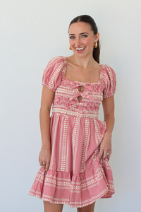 Woman wearing a red gingham mini dress with puff sleeves against a white background