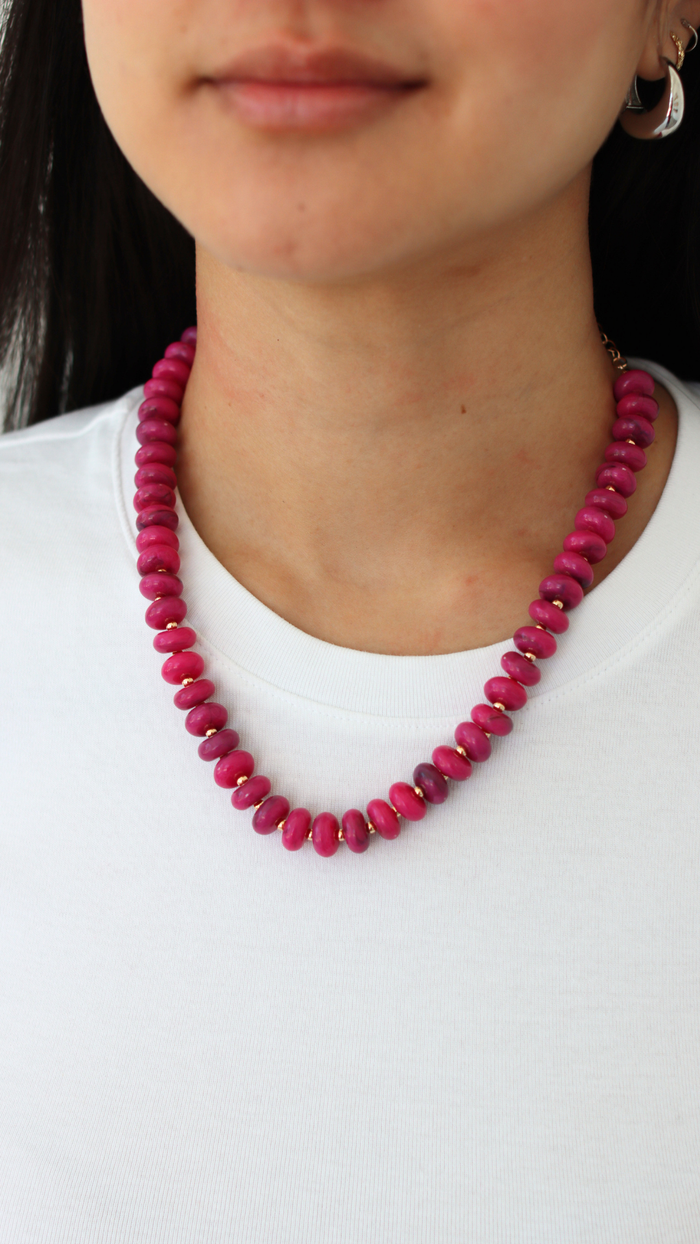 pink necklace on a woman wearing white shirt 