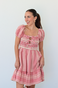 Woman wearing a red gingham mini dress with puff sleeves against a white background