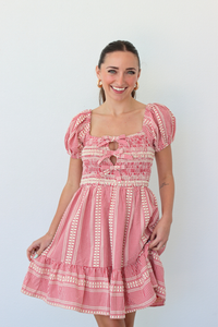 Woman wearing a red gingham mini dress with puff sleeves against a white background