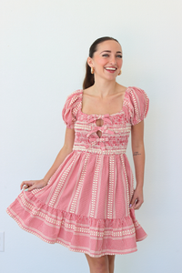 Woman wearing a red gingham mini dress with puff sleeves against a white background