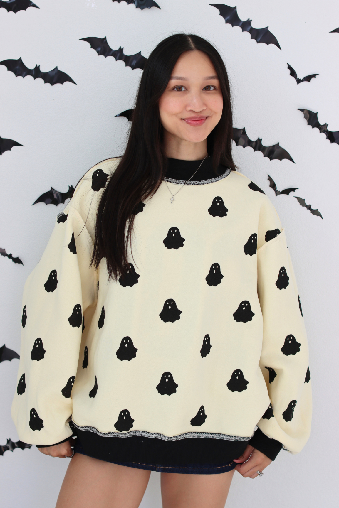 Woman wearing a white sweater with small ghost graphic 