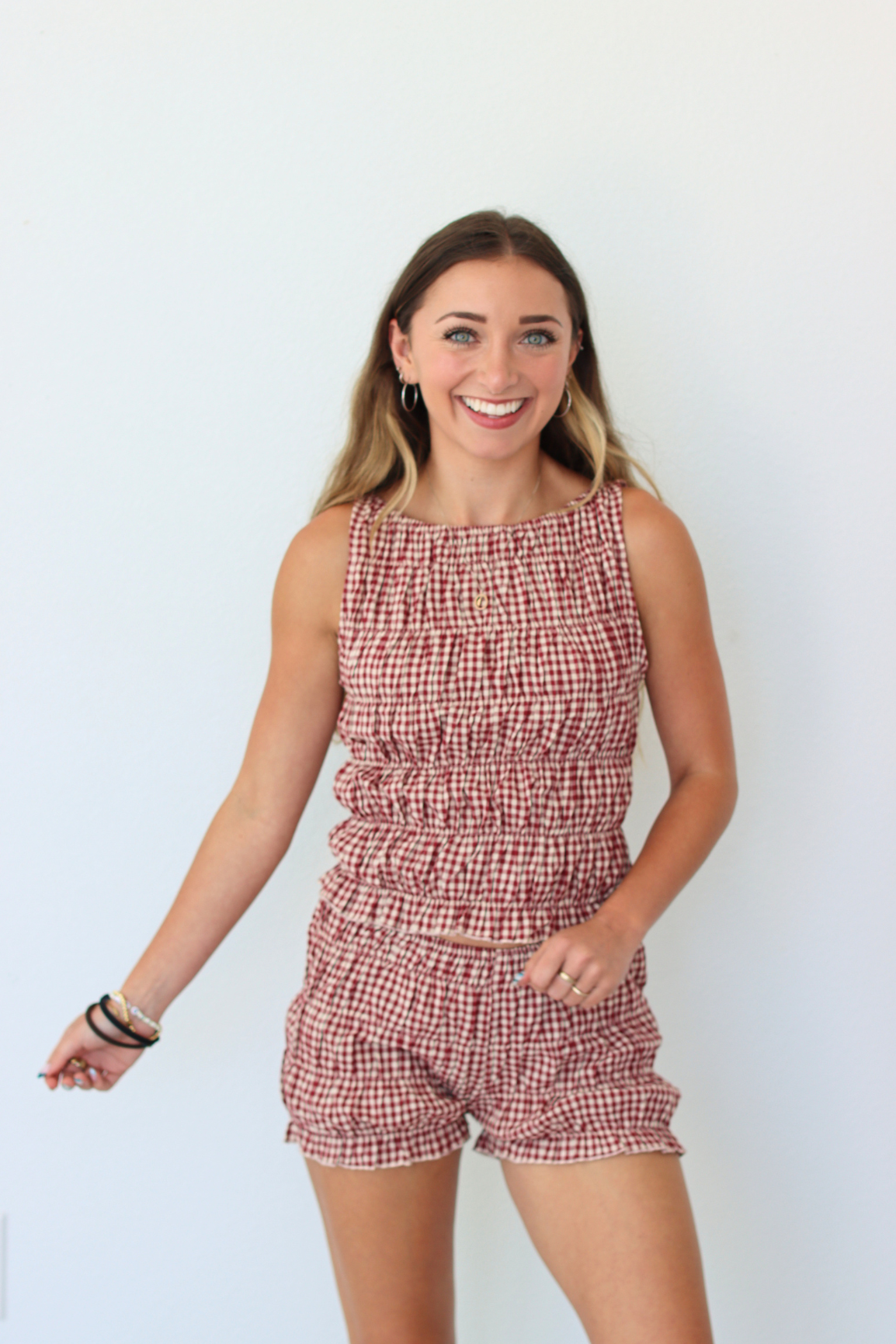 Woman wearing a red checkered outfit set against a white background