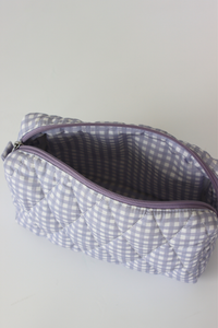 A quilted cosmetic pouch with a lavender and white gingham pattern, shown open to reveal a matching lavender interior lining.