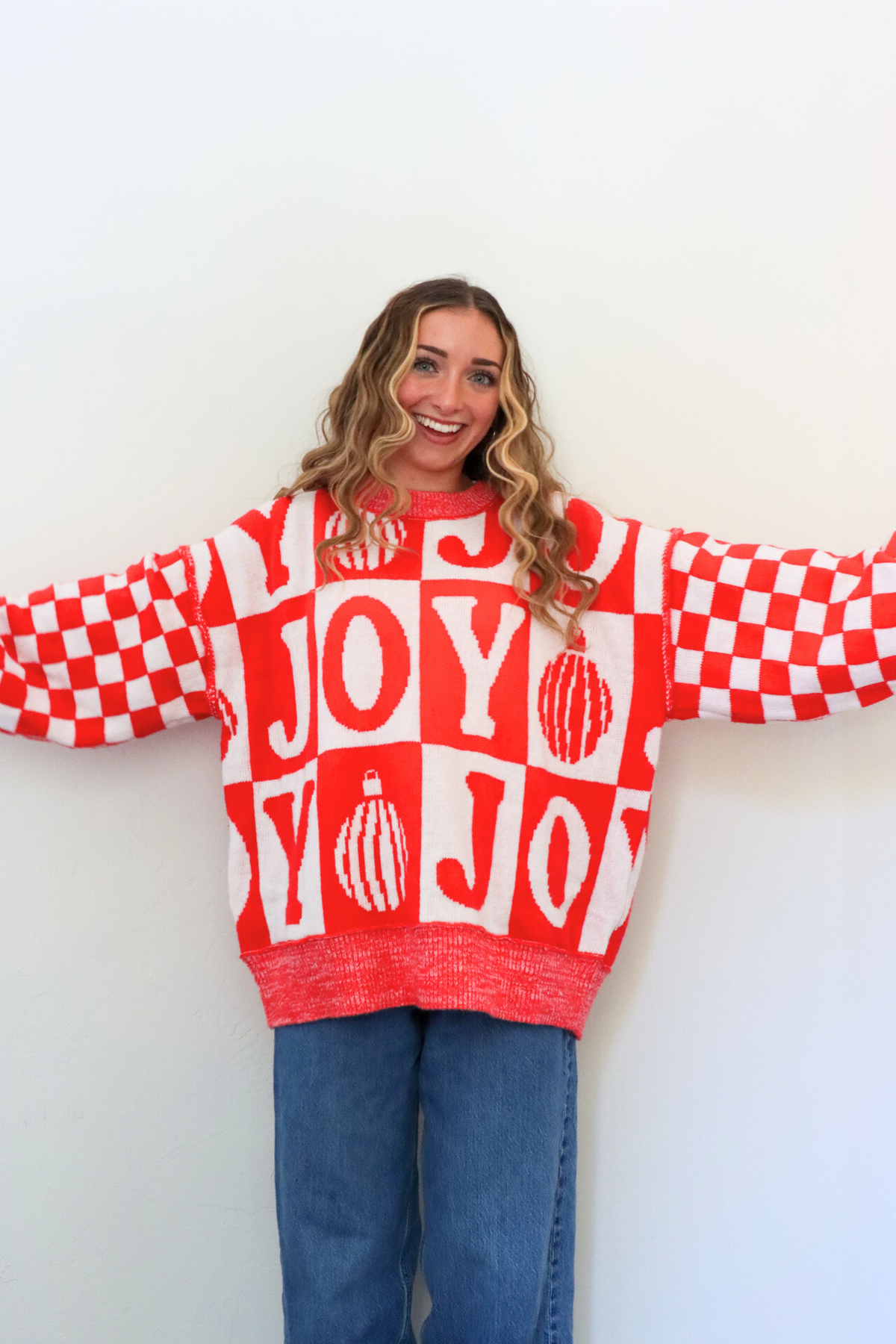 Person wearing a red and white checkered sweater with 'JOY' text against a white background