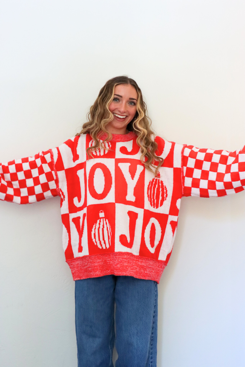 Person wearing a red and white checkered sweater with 'JOY' text against a white background