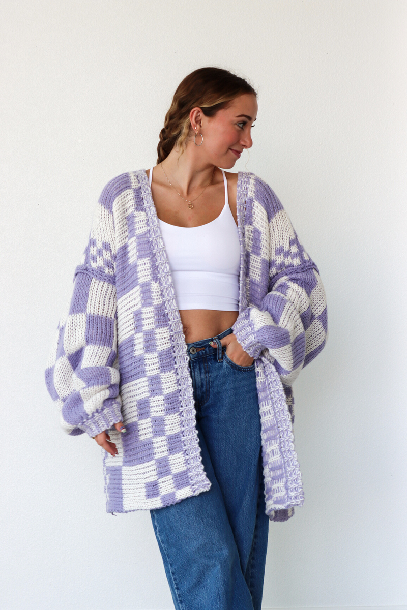 Woman wearing a purple and white checkered cardigan against a white background