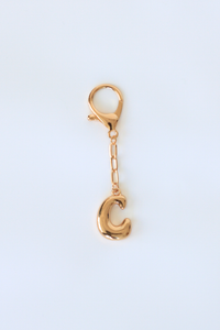 Gold letter 'C' charm on a white background