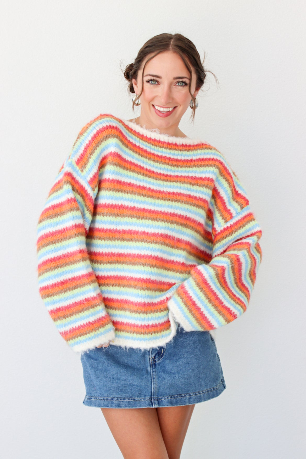 Woman wearing a multi color striped sweater with a denim mini skirt 