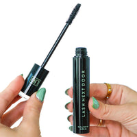 Mascara with 'Lash Next Door' branding held by a hand on a white background