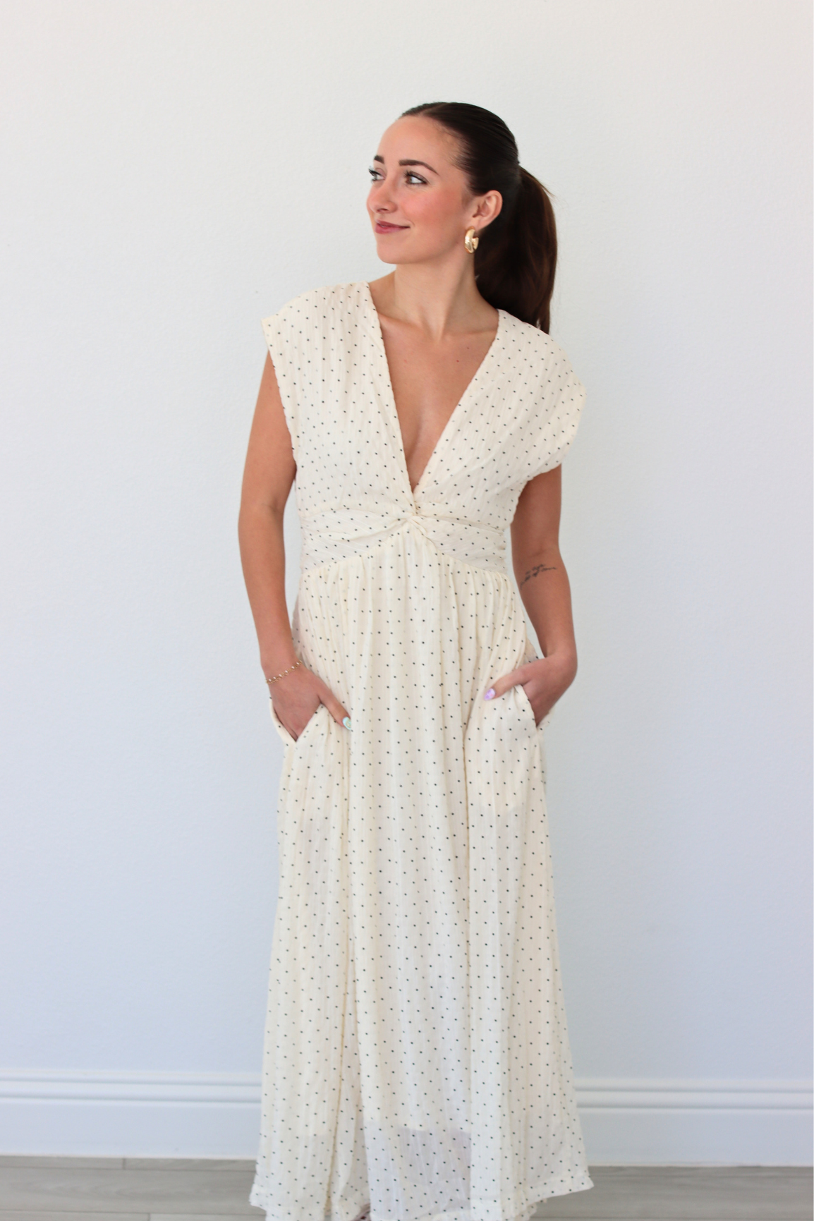 Woman wearing a white polka dot dress against a plain background