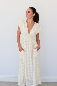 Woman wearing a white polka dot dress against a plain background