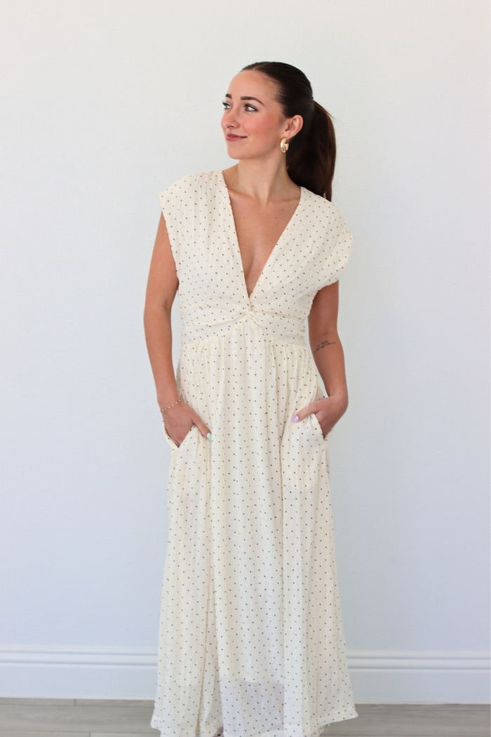 Woman wearing a white polka dot dress against a plain background