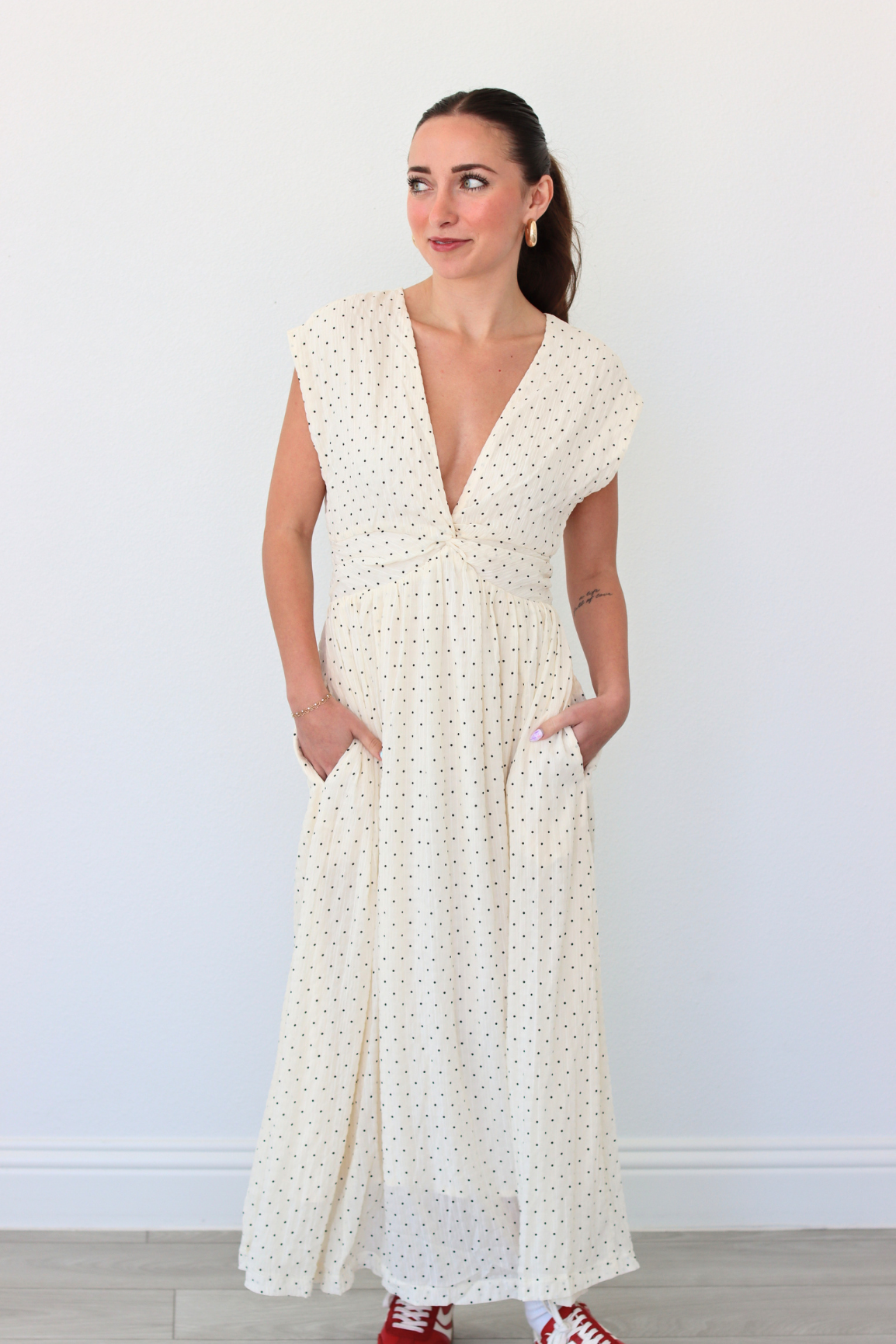 Woman wearing a white polka dot dress against a plain background