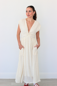 Woman wearing a white polka dot dress against a plain background