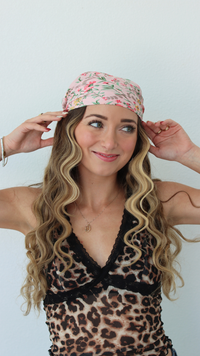Woman wearing a leopard print top and floral headband against a white background