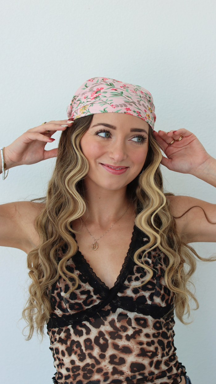 Woman wearing a leopard print top and floral headband against a white background
