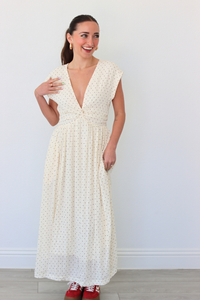 Woman wearing a white polka dot dress against a plain background