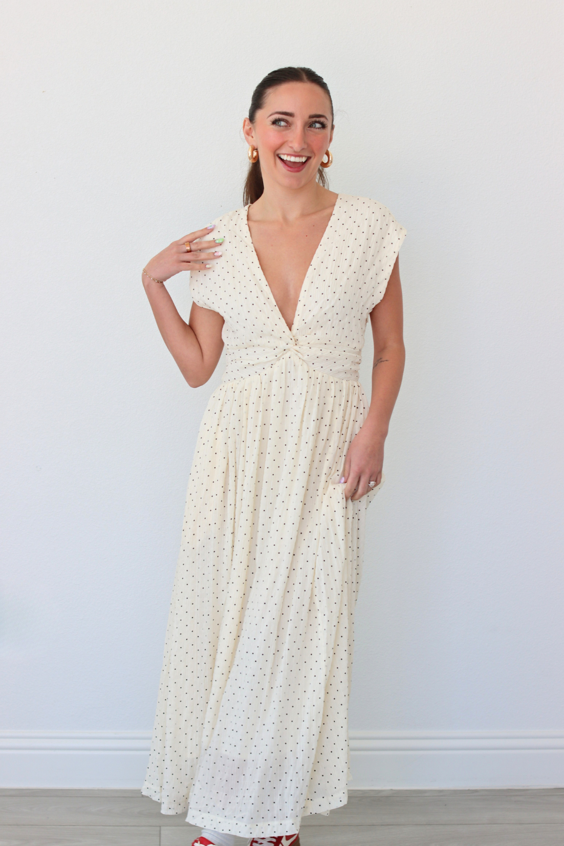Woman wearing a white polka dot dress against a plain background