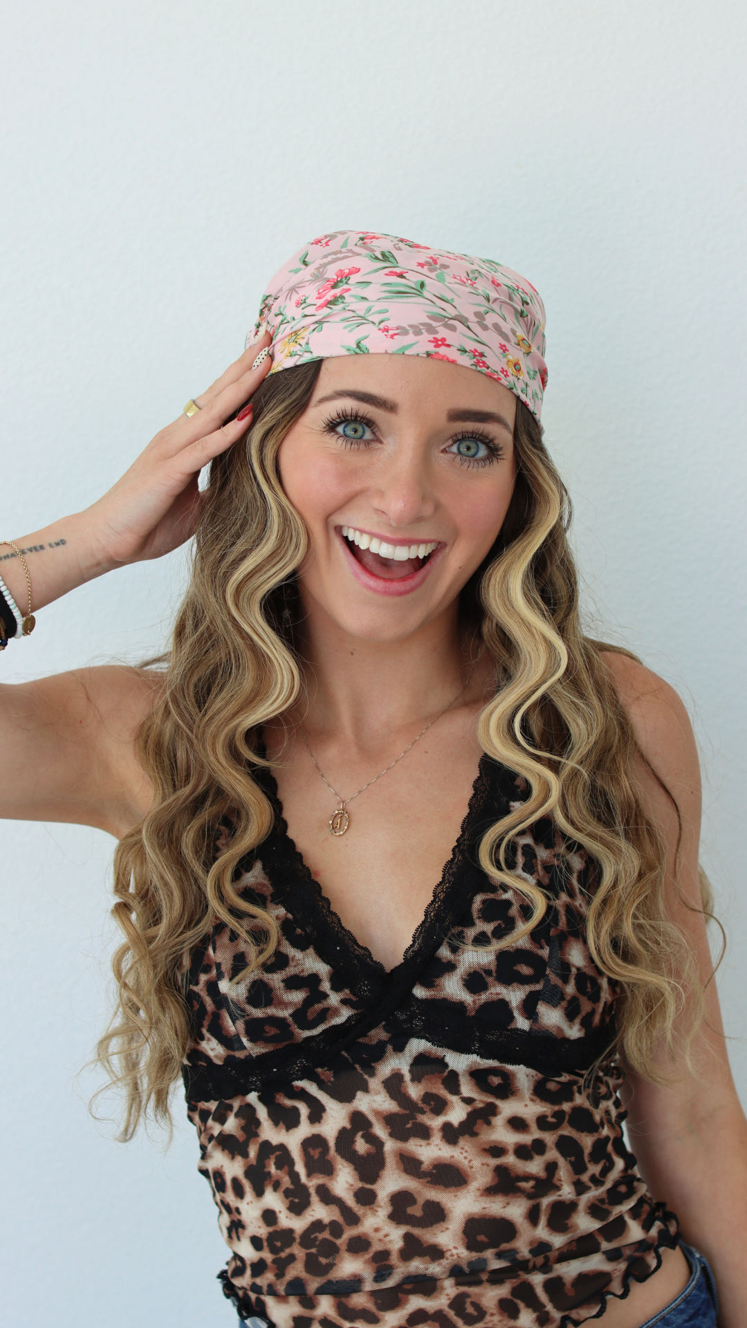 Woman wearing a floral headband and leopard print top against a white background