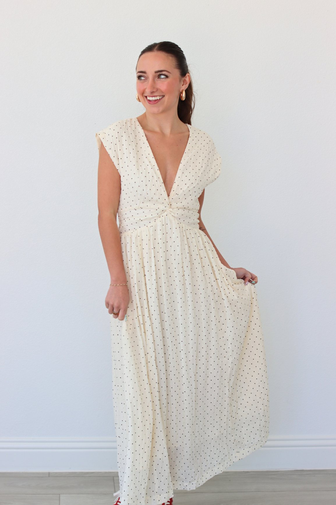 Woman wearing a white polka dot dress against a plain background