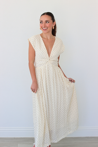 Woman wearing a white polka dot dress against a plain background
