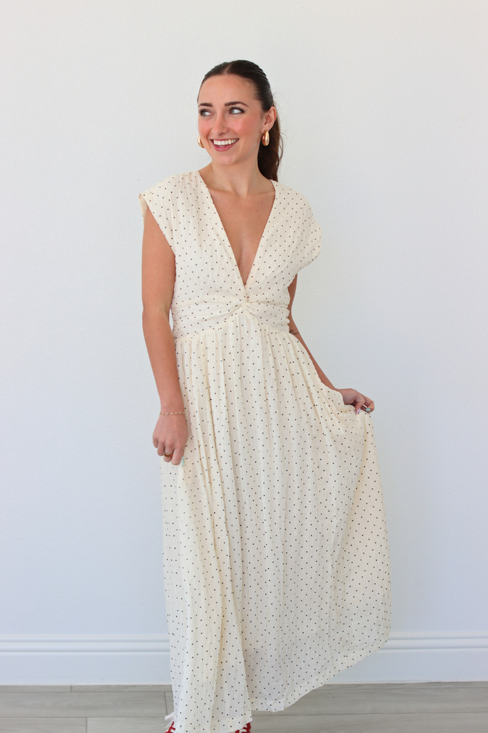 Woman wearing a white polka dot dress against a plain background