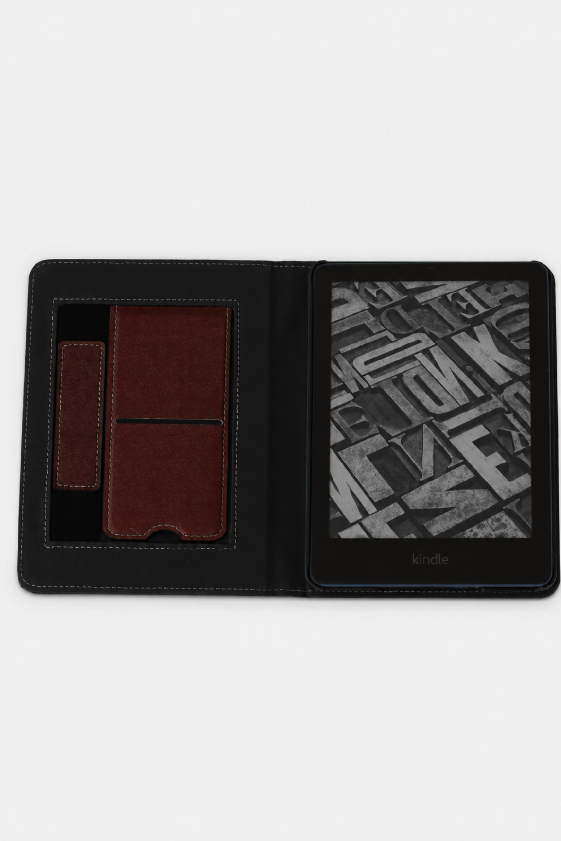 A dark red folio-style Kindle e-reader case shown open on a white background, with a kickstand and hand strap 