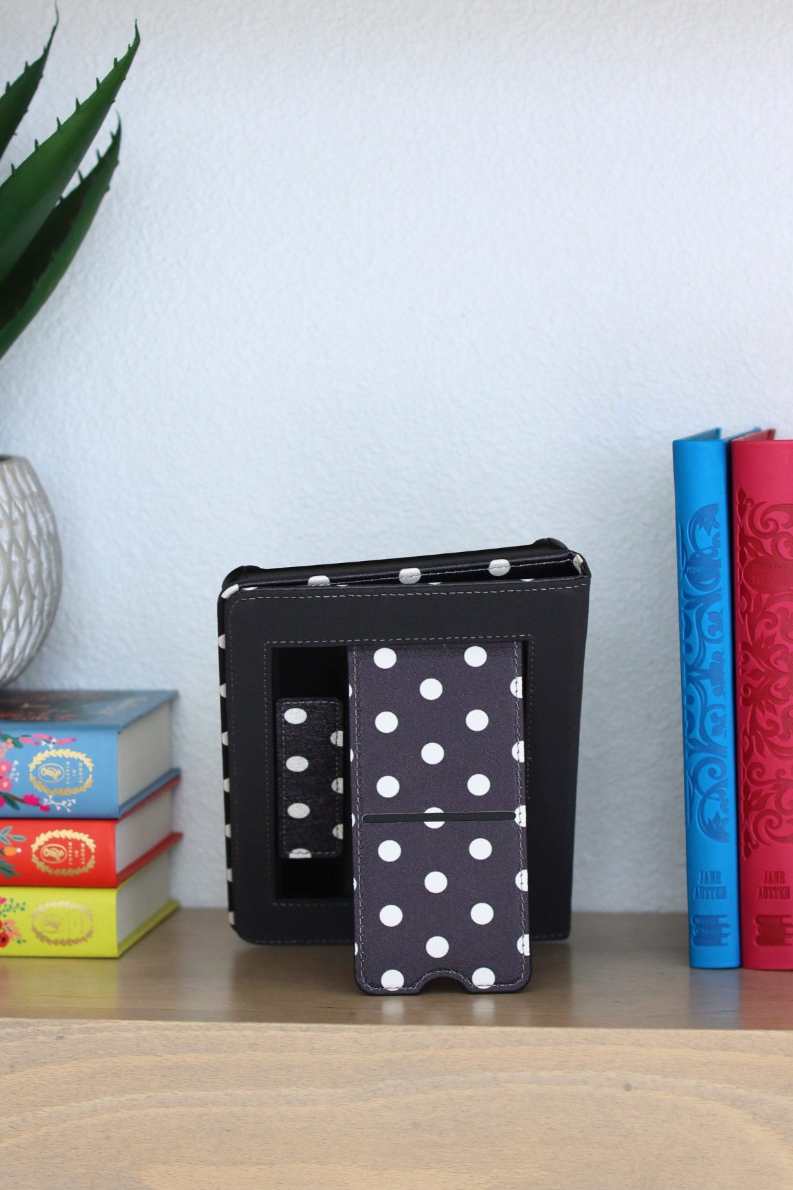Black case with white polka dots on a shelf with books