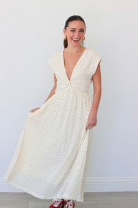 Woman wearing a white polka dot dress against a plain background