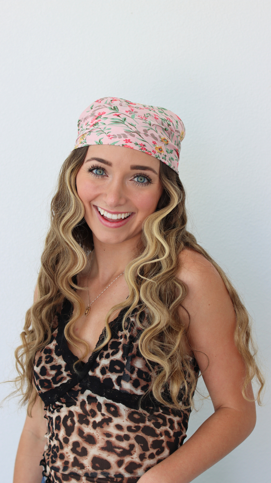 Woman wearing a leopard print top and colorful headband against a white background
