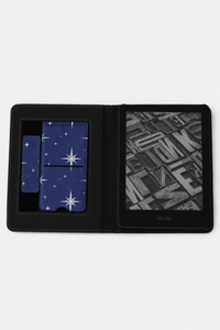 A black leather Kindle e-reader case shown open on a white background, featuring a blue starry night sky pattern on the card slots and a black-and-white book cover displayed on the screen.