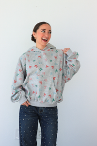 Woman wearing a gray hoodie with colorful patterns against a white background