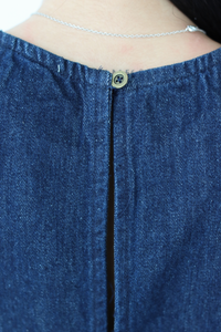 Close-up of a blue denim top with a button detail.