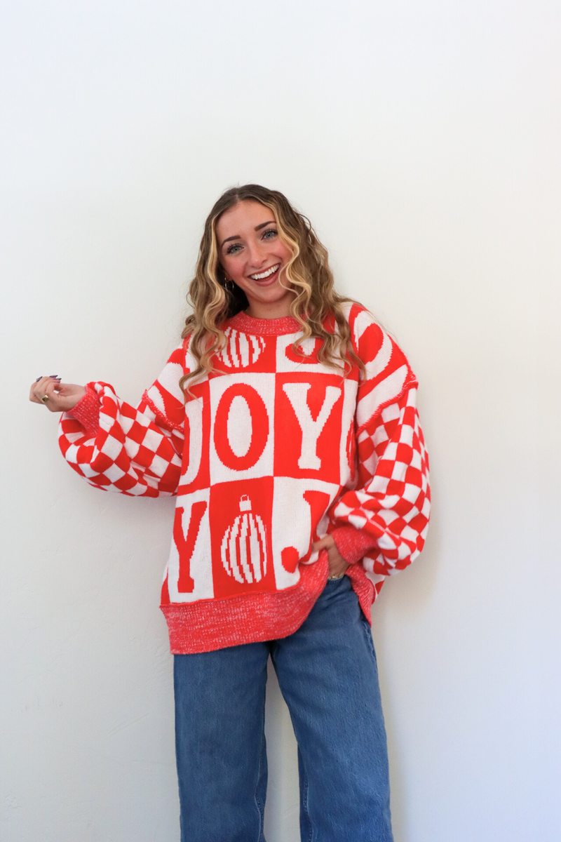 Person wearing a red and white checkered sweater with 'JOY' text against a white background