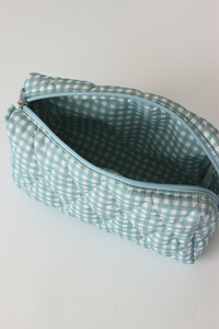 A quilted cosmetic pouch with a light blue and white gingham pattern, shown open to reveal its matching interior lining on a plain white background.